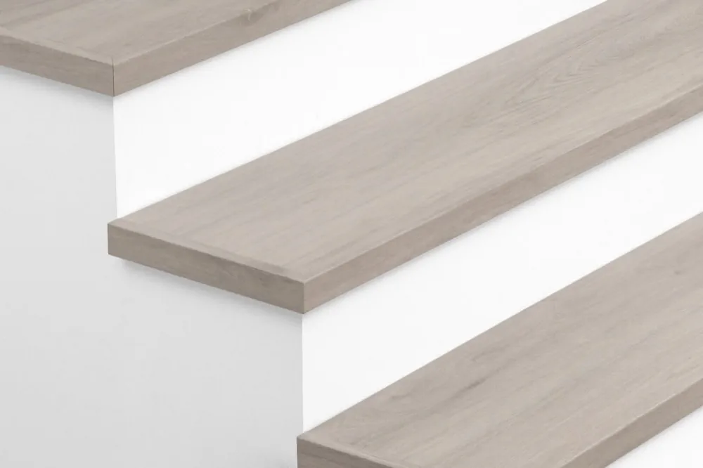 Closeup view of Urban Surfaces' All-In-One SPC Stair Treads installed on a staircase. Color is 2907 Bristol Harbor from the T Molding product line.2907 Bristol Harbor