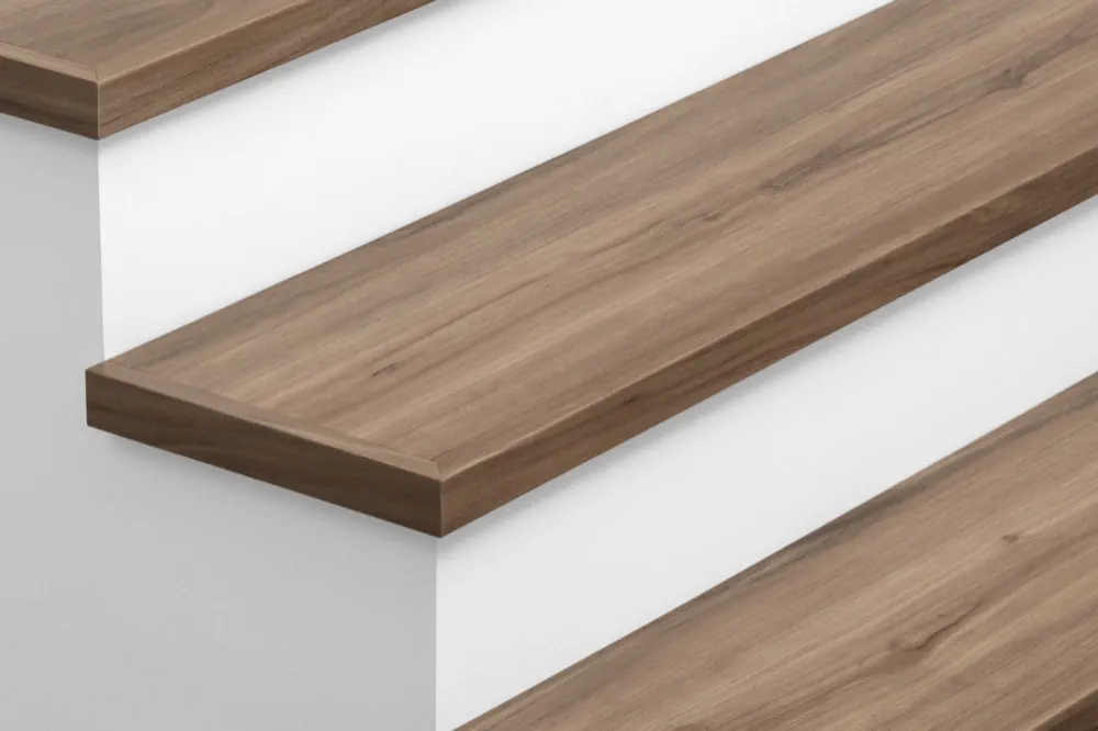 Closeup view of Urban Surfaces' All-In-One SPC Stair Treads installed on a staircase. Color is 2914 Berlin Terrace from the T Molding product line.2914 Berlin Terrace